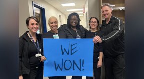 nurses hold up blue sign reading WE WON